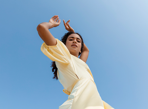 young woman dancing sky background